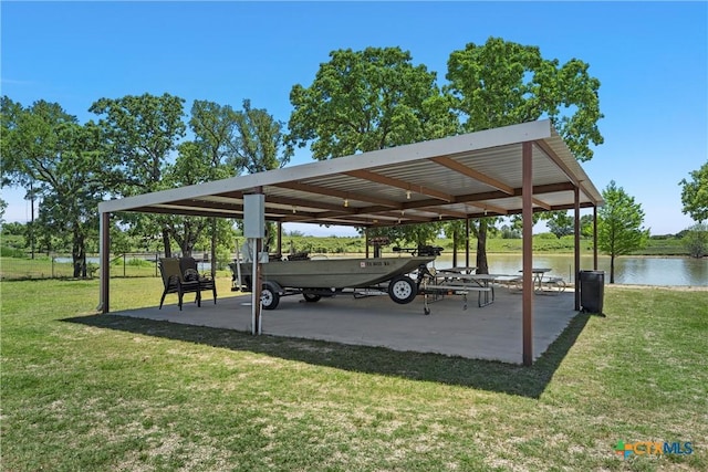 view of home's community with a detached carport, a lawn, and a water view