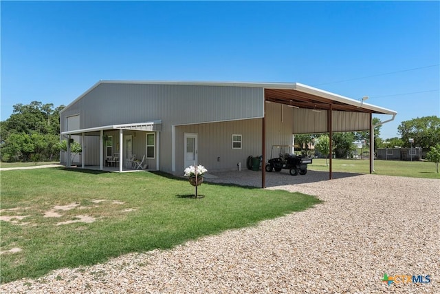 rear view of property with a lawn, driveway, and an attached carport