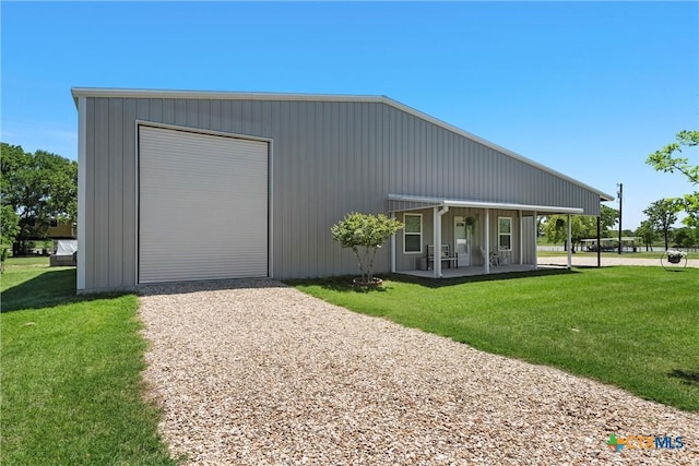 view of front of home featuring a detached garage, driveway, a front yard, and covered porch