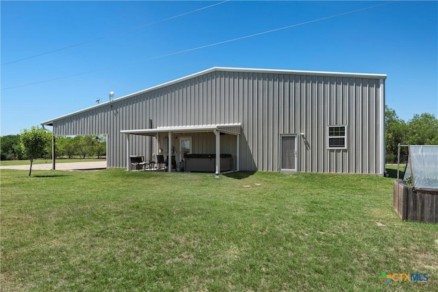 back of property featuring a hot tub, a yard, and board and batten siding