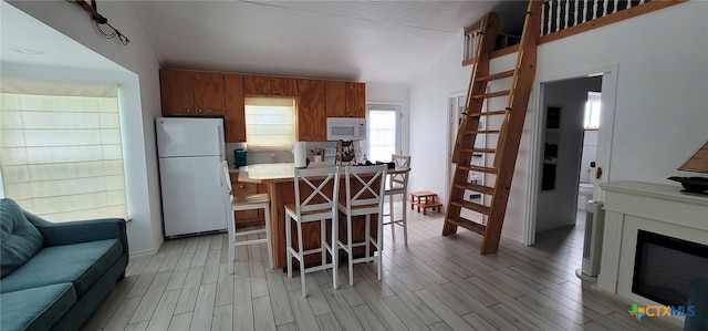 101 E Saint Louis Ave, Seadrift, TX 77983 - kitchen featuring white appliances, vaulted ceiling, open floor plan, light countertops, and a kitchen bar
