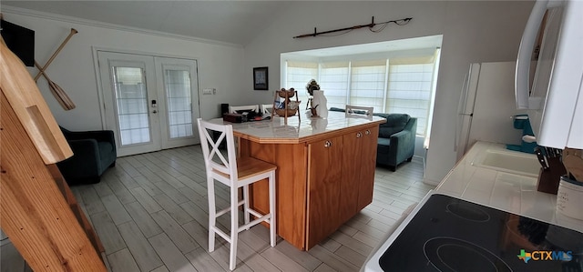 101 E Saint Louis Ave, Seadrift, TX 77983 - kitchen featuring lofted ceiling, french doors, tile countertops, brown cabinets, and a kitchen breakfast bar