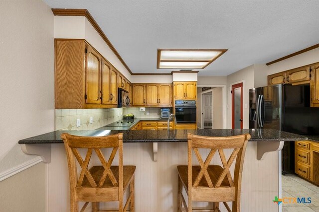 312 Beaver Loop, Temple, TX 76502 - kitchen featuring black appliances, decorative backsplash, a peninsula, crown molding, and brown cabinetry