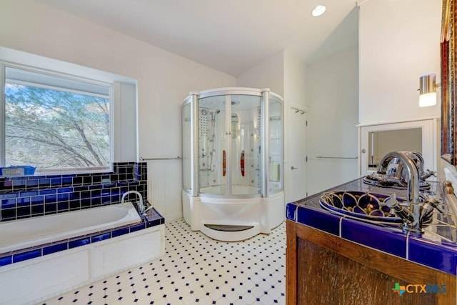 full bathroom featuring a stall shower, a bath, and a sink
