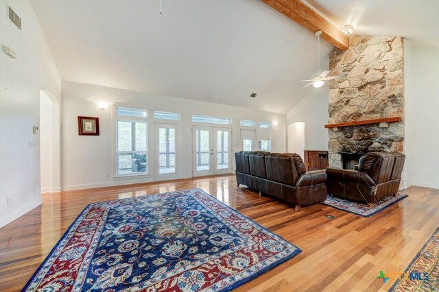 living area with wood finished floors, visible vents, a ceiling fan, and arched walkways