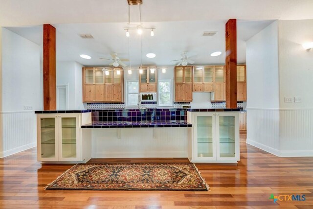 bar featuring visible vents, light wood-type flooring, and a ceiling fan