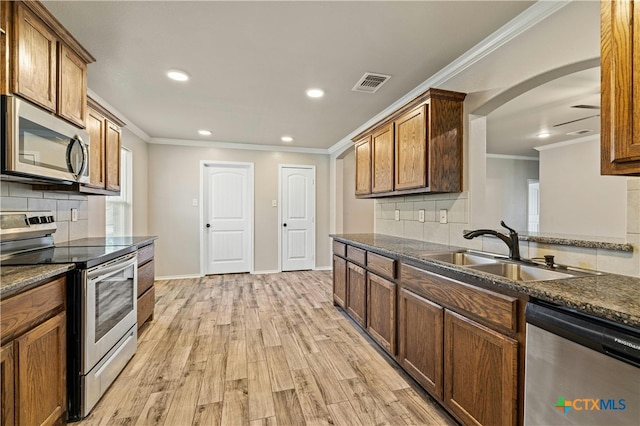 kitchen with stainless steel appliances, ornamental molding, light hardwood / wood-style flooring, and tasteful backsplash