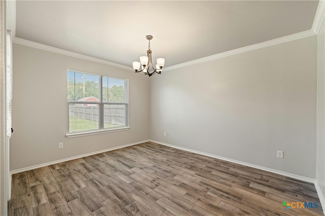 empty room with wood-type flooring, an inviting chandelier, and ornamental molding