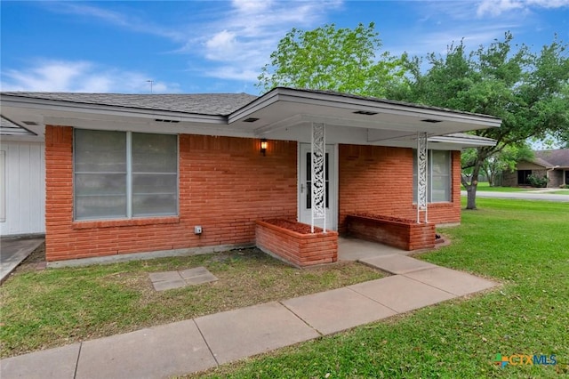 view of front of property featuring a front lawn, brick siding, and a shingled roof