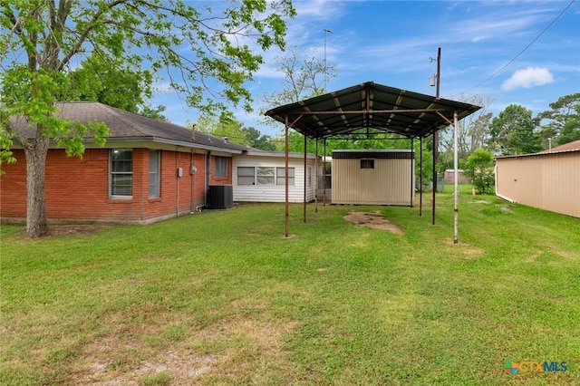 view of yard featuring cooling unit, driveway, an outbuilding, a carport, and a storage unit