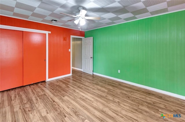 unfurnished bedroom with baseboards, wood finished floors, visible vents, and a closet