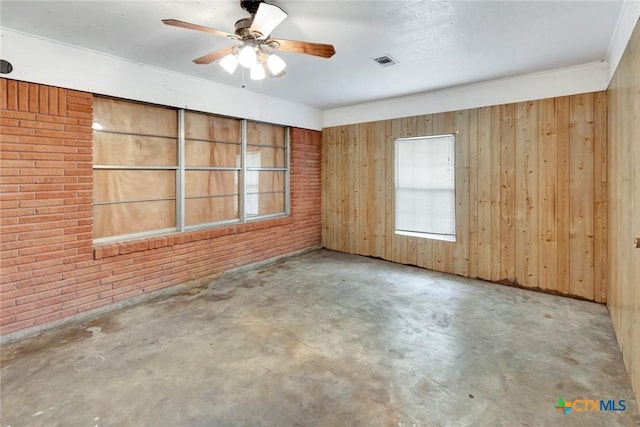 unfurnished room featuring concrete floors, visible vents, a ceiling fan, and a wealth of natural light