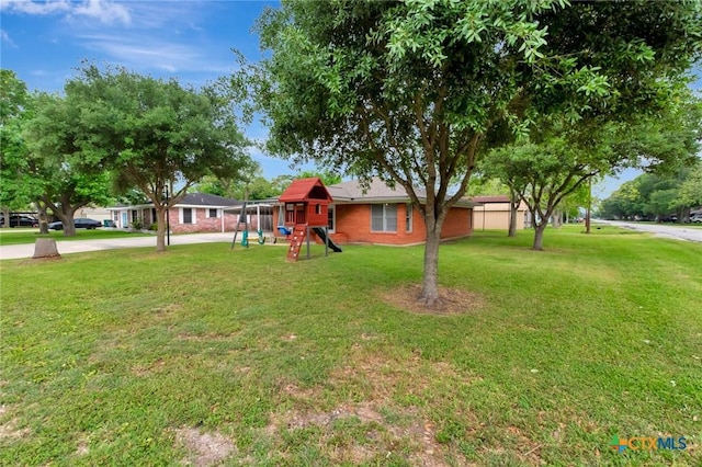 view of yard with concrete driveway and a playground