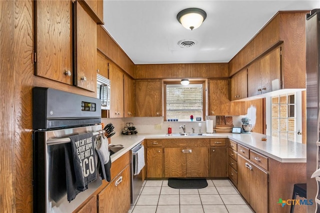 kitchen featuring a wealth of natural light, appliances with stainless steel finishes, visible vents, and brown cabinets