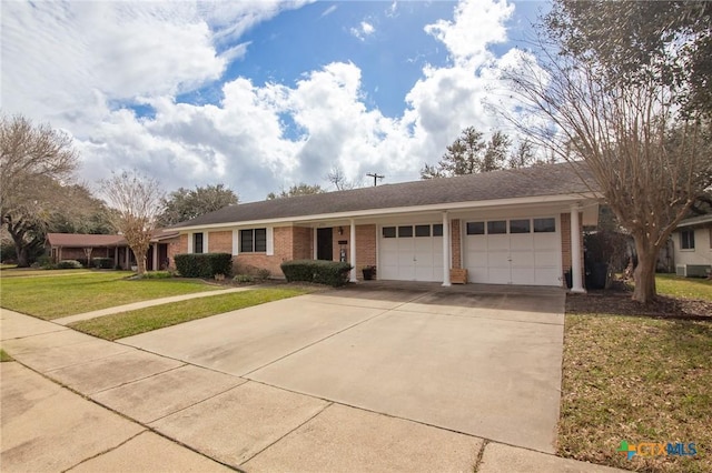 single story home featuring a front yard, brick siding, driveway, and an attached garage