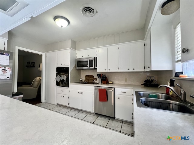 kitchen featuring visible vents, black appliances, a sink, white cabinets, and light tile patterned floors