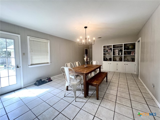 unfurnished dining area with light tile patterned floors, built in shelves, a healthy amount of sunlight, and a chandelier