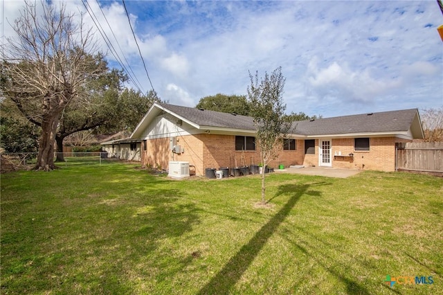 back of property with a fenced backyard, a lawn, and brick siding