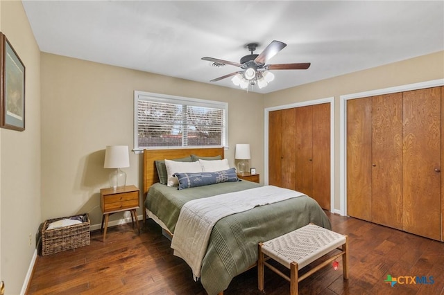 bedroom featuring two closets, a ceiling fan, baseboards, and wood finished floors