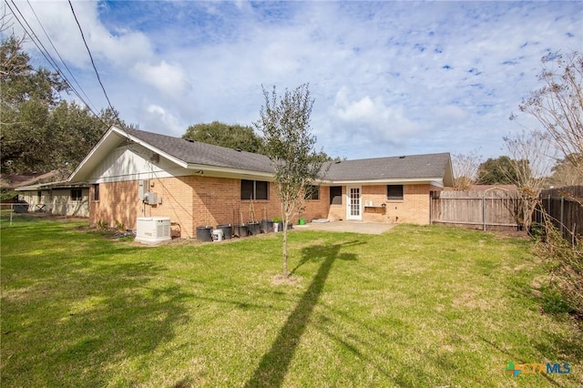 back of house with brick siding, a yard, a fenced backyard, and a patio