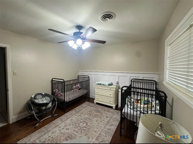 2701 College Dr, Victoria, TX 77901 - bedroom with dark wood-style floors, ceiling fan, and a wainscoted wall