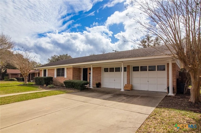 single story home with a front yard, concrete driveway, brick siding, and an attached garage