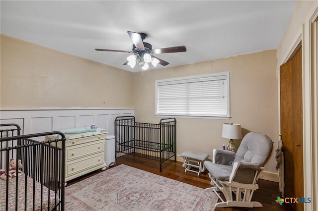 bedroom with a wainscoted wall, a decorative wall, and wood finished floors