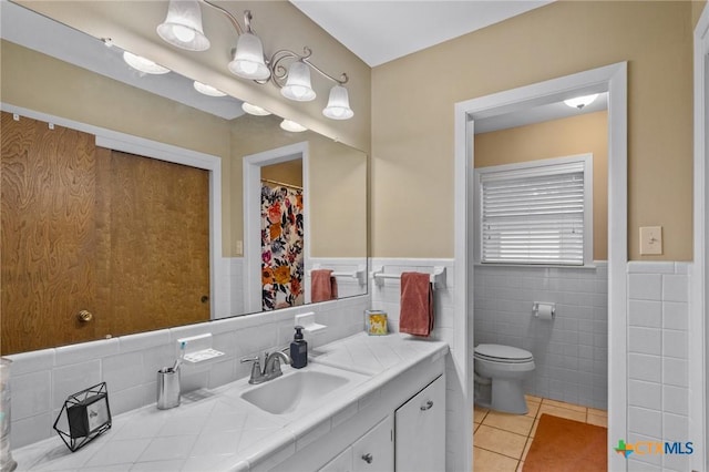 bathroom featuring a wainscoted wall, toilet, vanity, and tile patterned floors