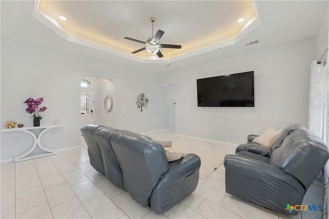 living room with a raised ceiling and ceiling fan
