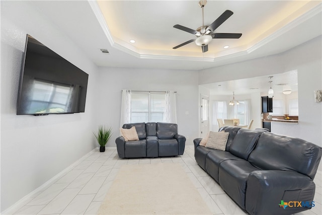 living room with a raised ceiling and ceiling fan