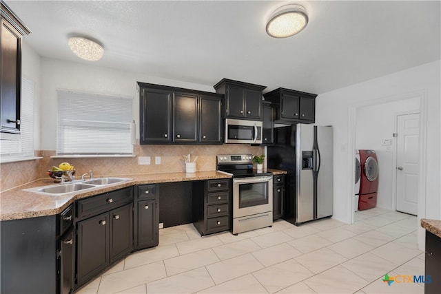 kitchen with sink, decorative backsplash, stainless steel appliances, and washing machine and dryer