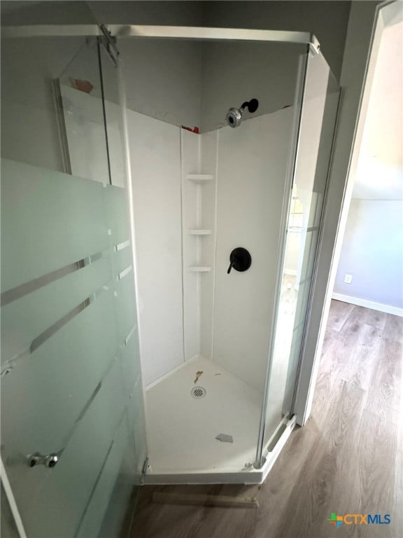 bathroom featuring an enclosed shower and hardwood / wood-style flooring