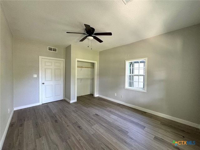 unfurnished bedroom with a textured ceiling, ceiling fan, a closet, and dark hardwood / wood-style floors