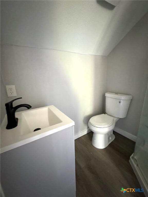 bathroom featuring hardwood / wood-style flooring, vanity, toilet, and lofted ceiling