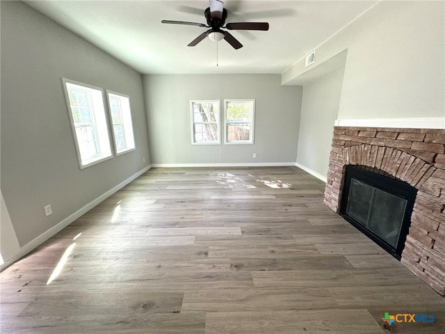 unfurnished living room featuring a stone fireplace, ceiling fan, and light wood-type flooring