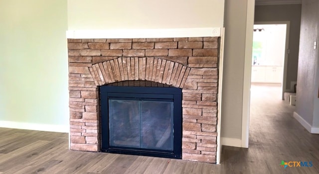 room details featuring a fireplace, hardwood / wood-style flooring, and crown molding