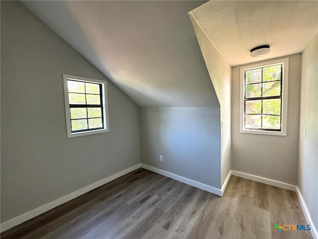 bonus room with wood-type flooring, a textured ceiling, and vaulted ceiling