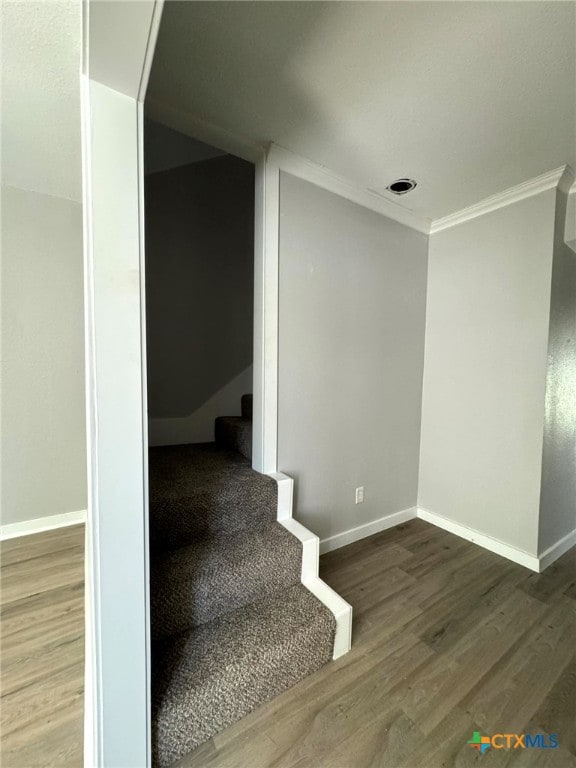 staircase with wood-type flooring and ornamental molding