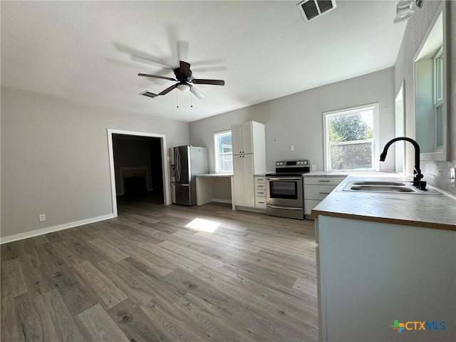 kitchen featuring appliances with stainless steel finishes, ceiling fan, sink, hardwood / wood-style floors, and white cabinetry