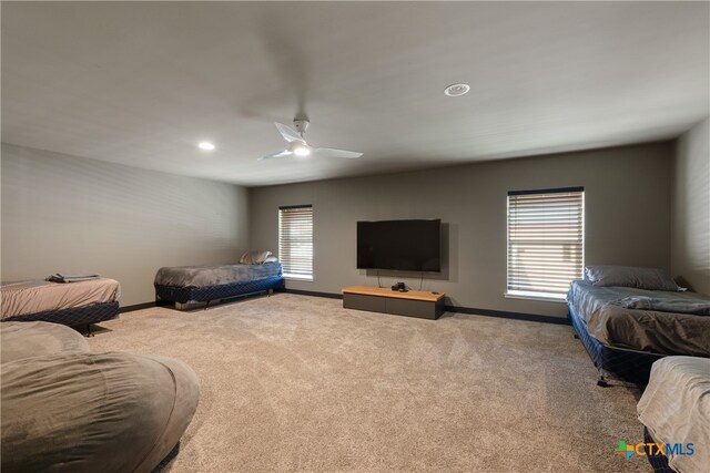 carpeted bedroom featuring multiple windows and ceiling fan