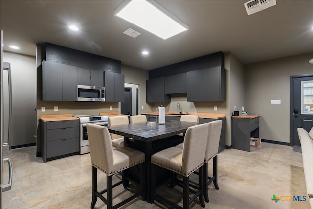 kitchen featuring appliances with stainless steel finishes, sink, a center island, and wood counters