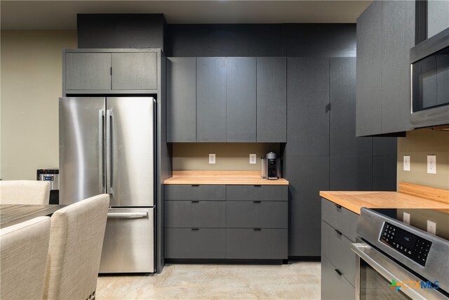 kitchen with stainless steel appliances, gray cabinets, and wood counters