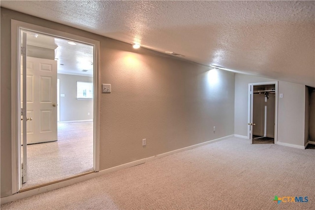 carpeted spare room with a textured wall, a textured ceiling, and baseboards