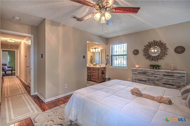 bedroom with a textured ceiling, visible vents, wood finished floors, and attic access