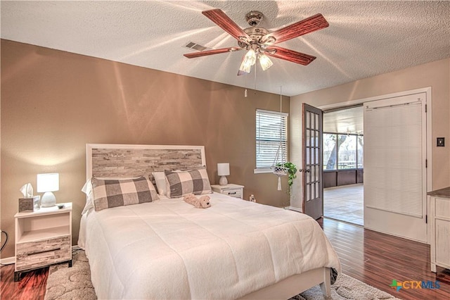 bedroom featuring a textured ceiling, wood finished floors, visible vents, and a ceiling fan