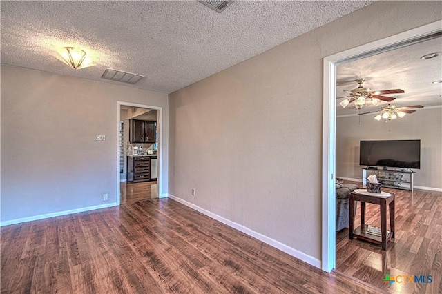 unfurnished room with a textured ceiling, wood finished floors, visible vents, and baseboards