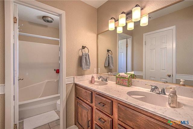 bathroom with double vanity, tile patterned flooring, bathtub / shower combination, and a sink