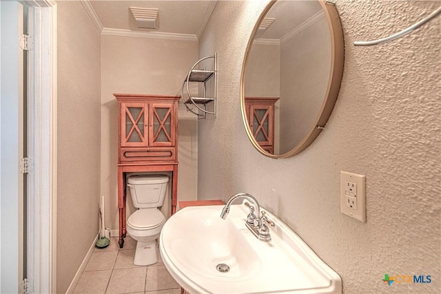 bathroom with a textured wall, toilet, ornamental molding, tile patterned floors, and a sink