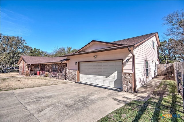 ranch-style house featuring stone siding, an attached garage, fence, and driveway