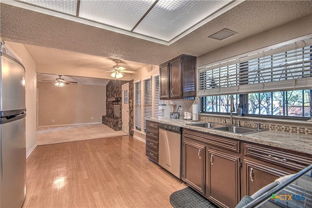 kitchen with a wealth of natural light, light wood-style flooring, stainless steel appliances, and a sink